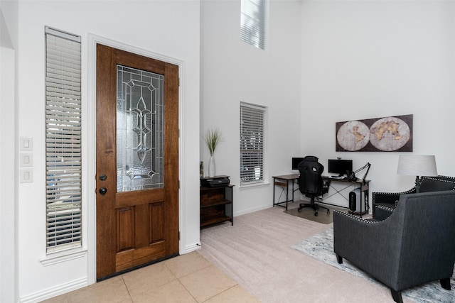 entryway with baseboards, carpet floors, a high ceiling, and tile patterned floors