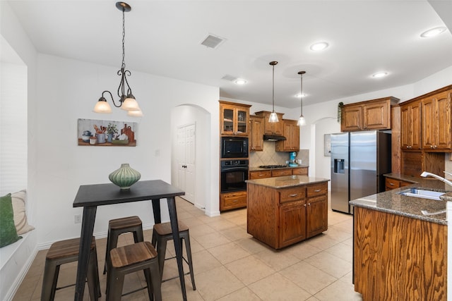 kitchen with visible vents, a kitchen island, a sink, under cabinet range hood, and black appliances