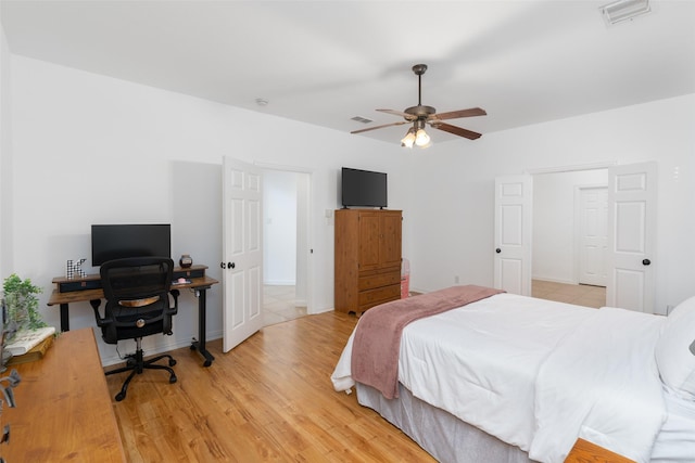 bedroom featuring light wood finished floors, an office area, a ceiling fan, and baseboards