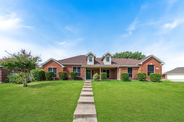 view of front of house with a shingled roof, brick siding, and a front lawn