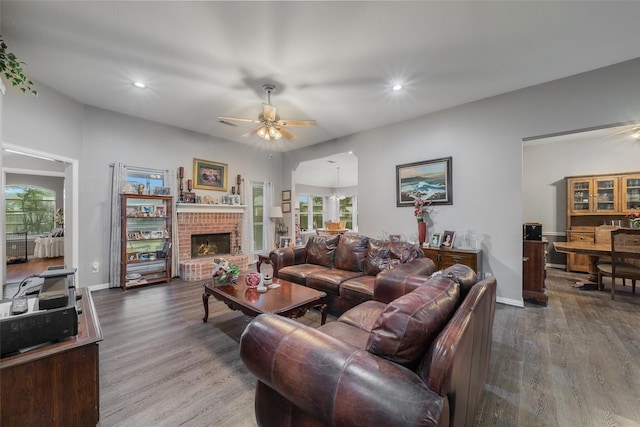 living area featuring a brick fireplace, a wealth of natural light, and wood finished floors