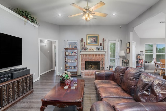 living room with ceiling fan, a brick fireplace, wood finished floors, and a healthy amount of sunlight