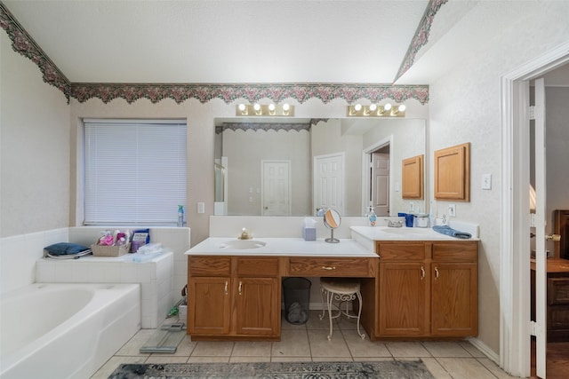 bathroom with a sink, double vanity, a garden tub, and tile patterned floors