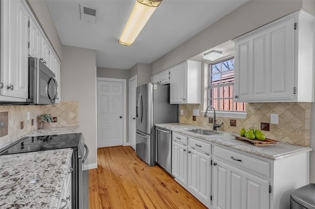 kitchen with stainless steel appliances, visible vents, a sink, and white cabinetry