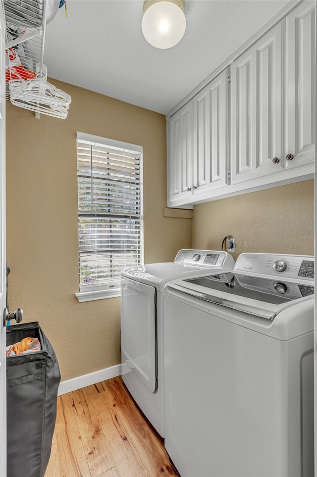 laundry area with cabinet space, baseboards, washer and clothes dryer, and light wood-style floors