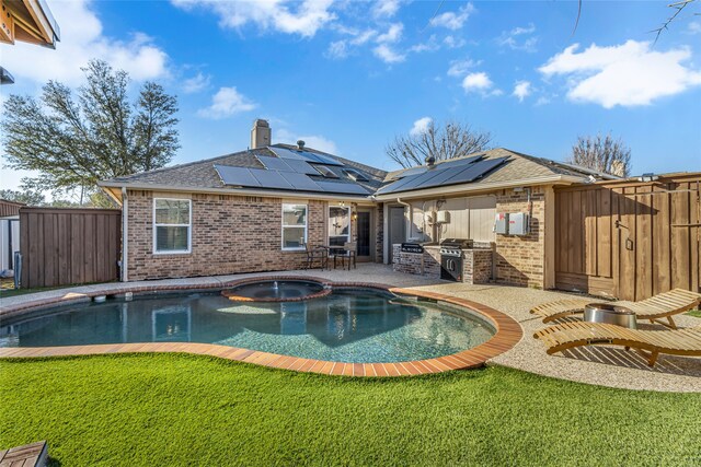 view of pool with a patio, an outdoor kitchen, a fenced backyard, a pool with connected hot tub, and a lawn