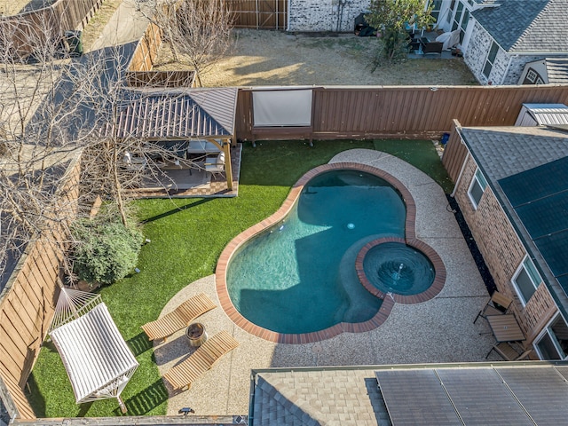 view of swimming pool featuring a pool with connected hot tub, a fenced backyard, and a lawn