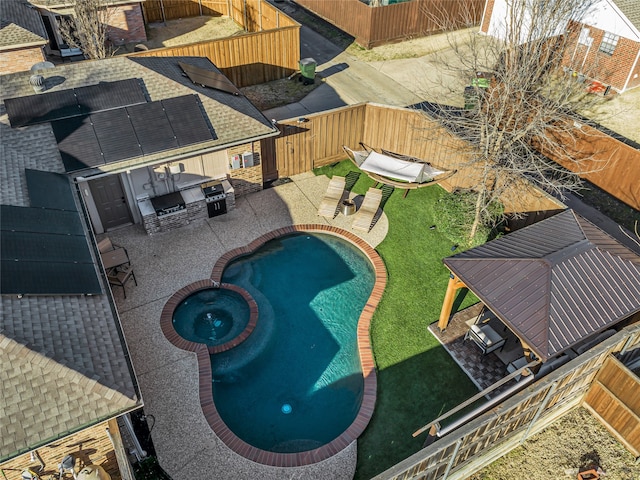 view of pool featuring a patio, exterior kitchen, a fenced backyard, and a pool with connected hot tub