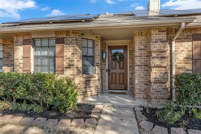 doorway to property with solar panels and brick siding