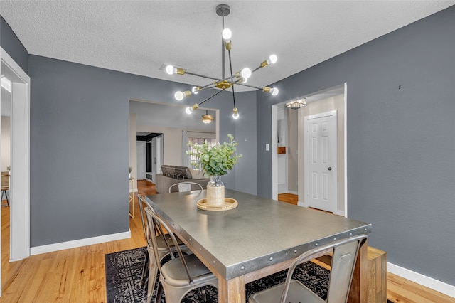 dining space with light wood-style floors, baseboards, and a textured ceiling