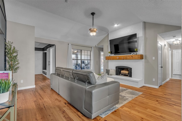 living area featuring lofted ceiling, a fireplace, a textured ceiling, and hardwood / wood-style floors