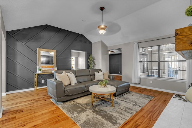 living room featuring a ceiling fan, lofted ceiling, baseboards, and wood finished floors