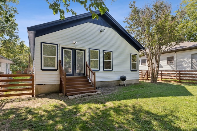 rear view of house featuring a lawn, fence, and entry steps