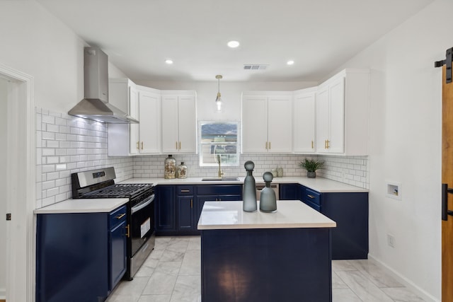 kitchen with visible vents, a sink, wall chimney range hood, blue cabinets, and stainless steel gas range oven