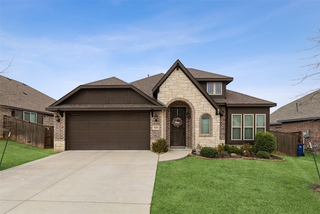 french country inspired facade with a garage, concrete driveway, fence, and a front lawn