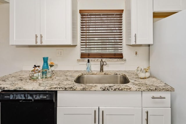 kitchen with black dishwasher, light stone counters, white cabinets, and a sink