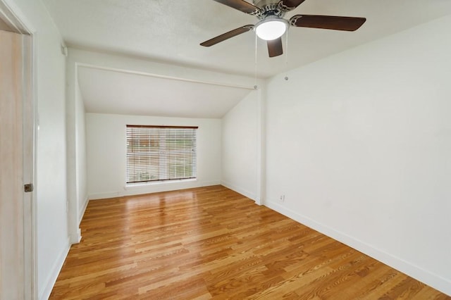 spare room with lofted ceiling, light wood-style floors, and baseboards