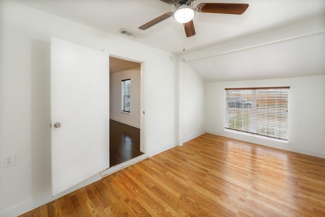 empty room with light wood-style floors, visible vents, plenty of natural light, and lofted ceiling with beams