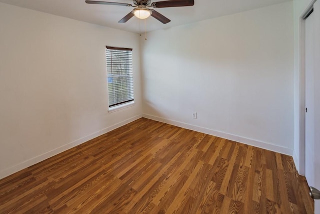 empty room with wood finished floors, a ceiling fan, and baseboards