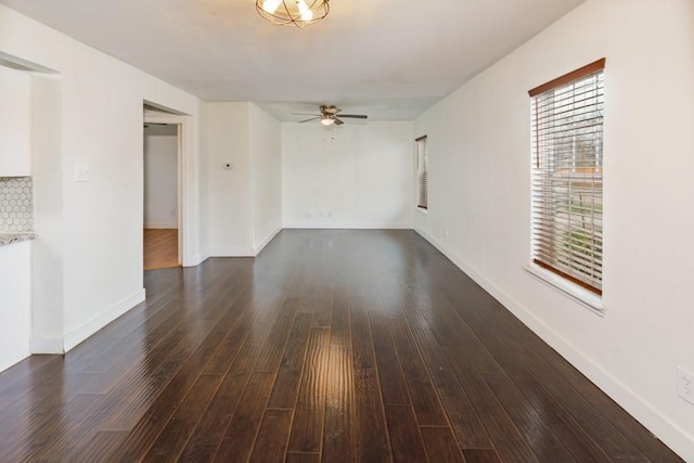 unfurnished living room with a ceiling fan, dark wood finished floors, and baseboards