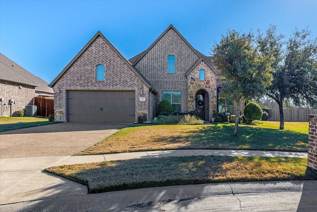 view of front of property with driveway, stone siding, fence, a front lawn, and brick siding