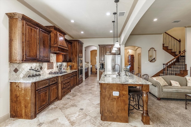 kitchen with arched walkways, a breakfast bar area, stainless steel appliances, visible vents, and a sink