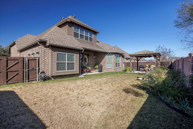 rear view of property featuring a gazebo, brick siding, a patio area, and a gate