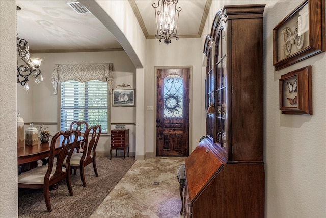 foyer with visible vents, arched walkways, an inviting chandelier, carpet, and crown molding