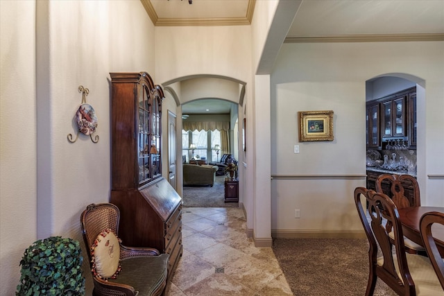 corridor with arched walkways, baseboards, light carpet, and crown molding