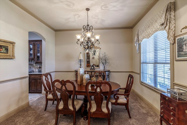 carpeted dining room with ornamental molding, arched walkways, a chandelier, and baseboards