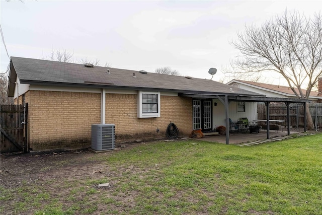 rear view of property featuring brick siding, fence, central AC unit, a yard, and a patio