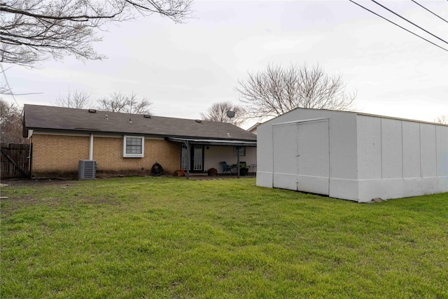 back of property with brick siding, a shed, a lawn, and central AC