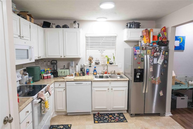 kitchen featuring white appliances, white cabinets, light countertops, and a sink