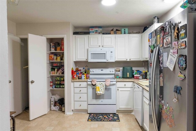 kitchen featuring white appliances, white cabinetry, and light countertops