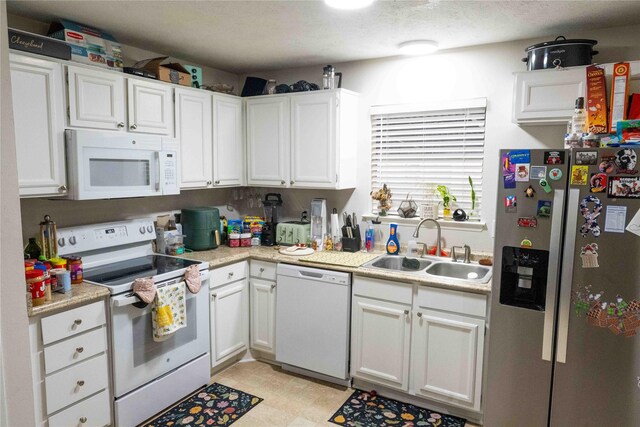 kitchen with white cabinetry, white appliances, light countertops, and a sink