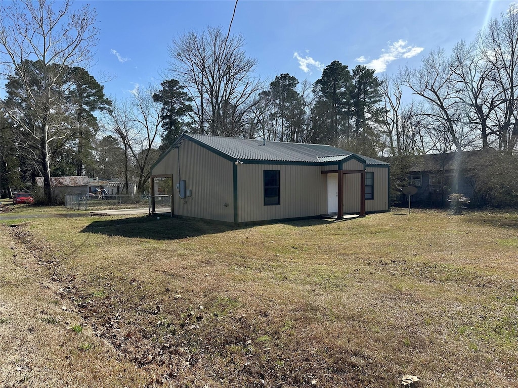 exterior space with metal roof and a lawn