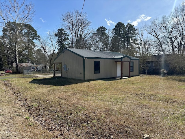 exterior space with metal roof and a lawn