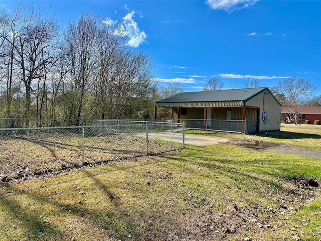 exterior space with metal roof, fence, driveway, and a lawn