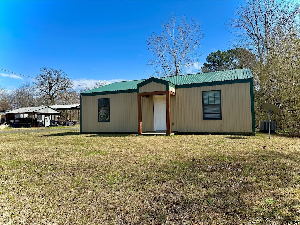 view of front of home featuring central air condition unit, a front lawn, metal roof, and a carport