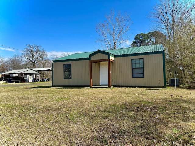 view of front of home featuring central air condition unit, a front lawn, metal roof, and a carport