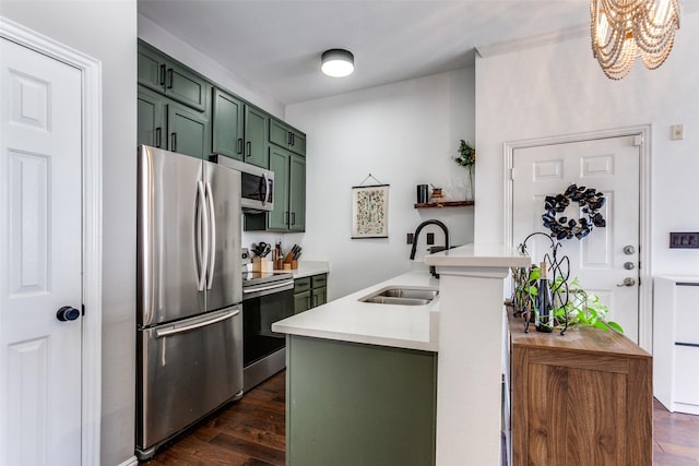 kitchen with dark wood finished floors, green cabinetry, stainless steel appliances, light countertops, and a sink