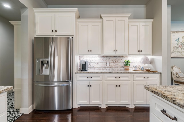 kitchen with light stone countertops, white cabinets, and stainless steel fridge with ice dispenser