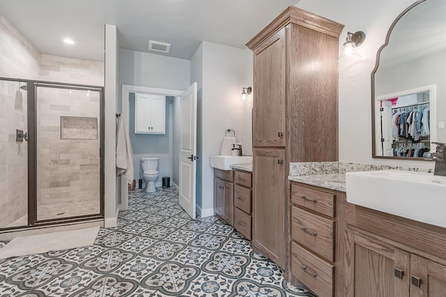 full bathroom featuring a sink, two vanities, a shower stall, and visible vents