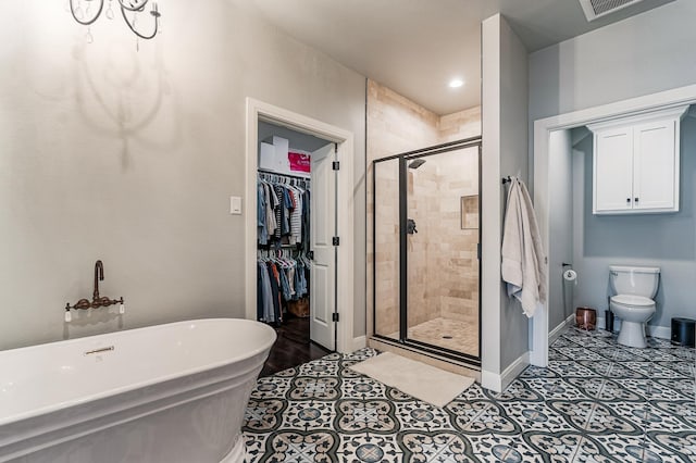 bathroom featuring tile patterned flooring, baseboards, a freestanding bath, a stall shower, and a walk in closet