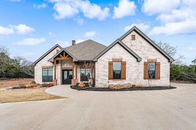 view of front of property with french doors, a chimney, a shingled roof, and brick siding