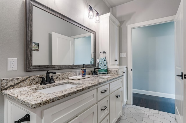 full bath featuring double vanity, baseboards, a sink, and tile patterned floors