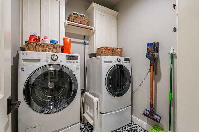 clothes washing area featuring washing machine and dryer, cabinet space, and baseboards