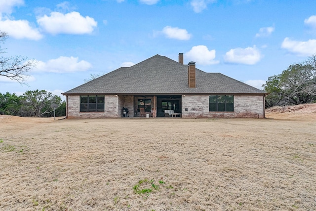 back of property with a patio area, roof with shingles, and a chimney