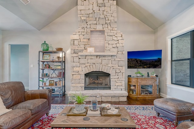 living room featuring a fireplace, vaulted ceiling, baseboards, and wood finished floors