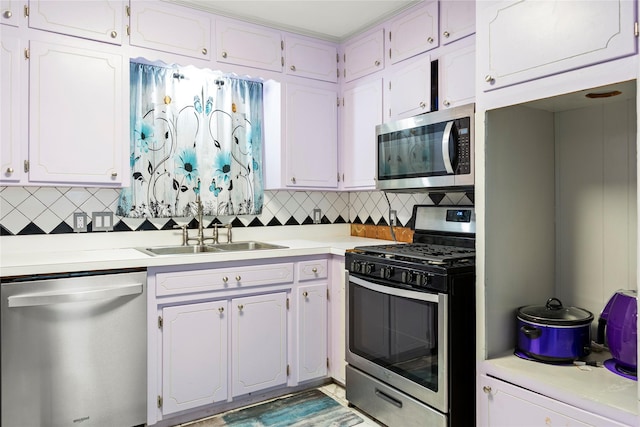 kitchen featuring white cabinets, appliances with stainless steel finishes, backsplash, and a sink